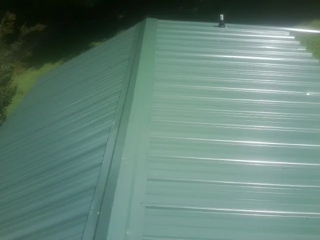 New green metal panels meeting at the ridge of a roof — Flat Roof Repair work by our crew in Lawson