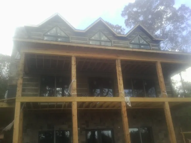 Dormers and porch framing on a large log home under construction — Roof Coating work by our crew in Lawson