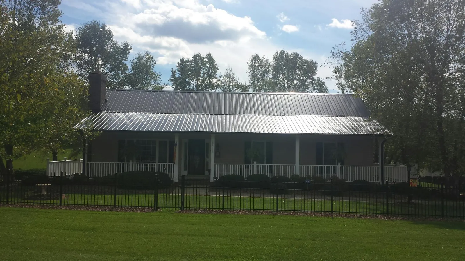 Gray metal roof on a brick ranch with a full width front porch — Gutter Guard Installation work by our crew in Lawson