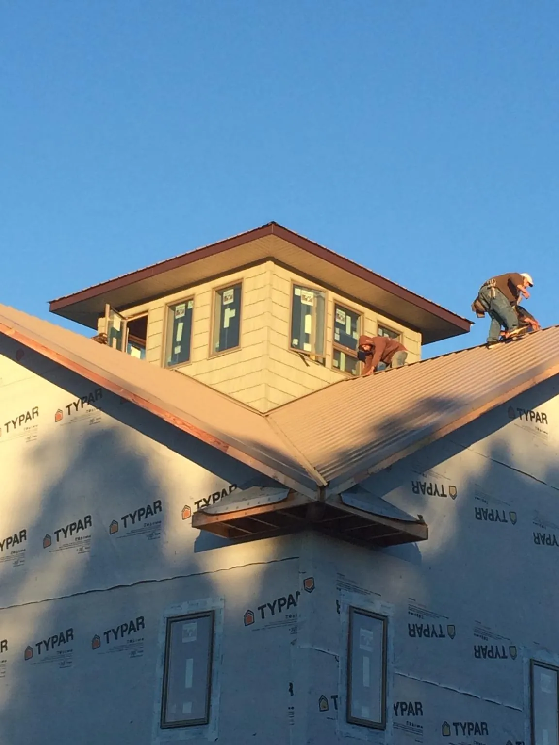 Roofers working around a rooftop cupola on a new metal roof at sunset — Roof Waterproofing in Lawson by Roofing Brothers